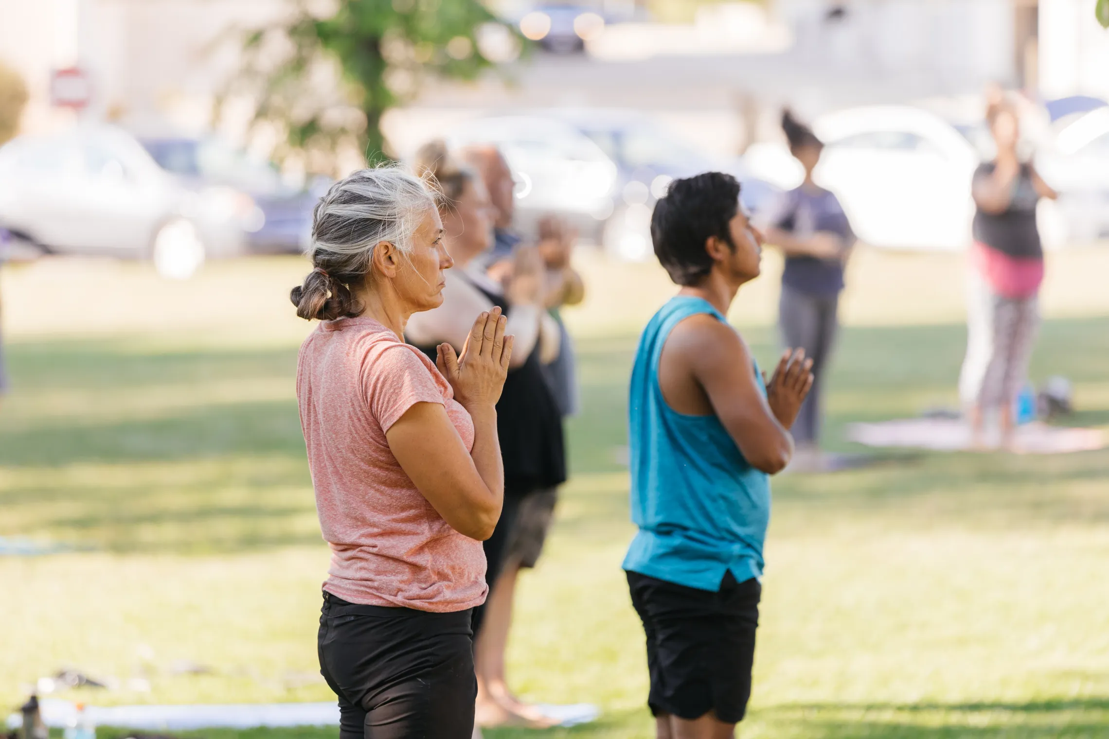 A woman and man doing yoga in a park.