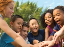 Group of 6 youth children grouped together putting their hands in the middle
