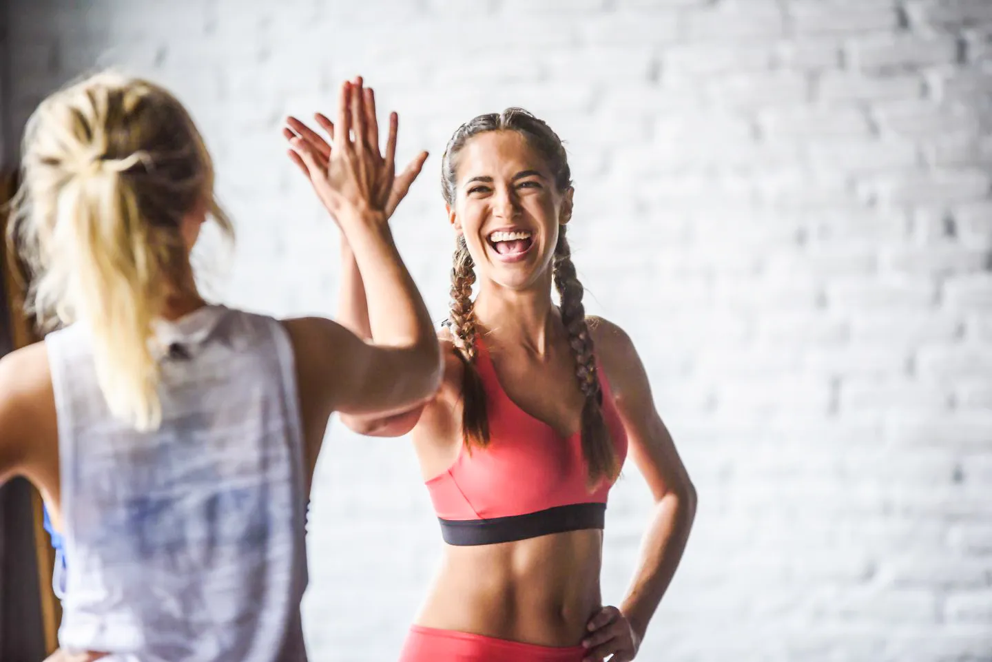Two female friends smiling and giving each other a high five.