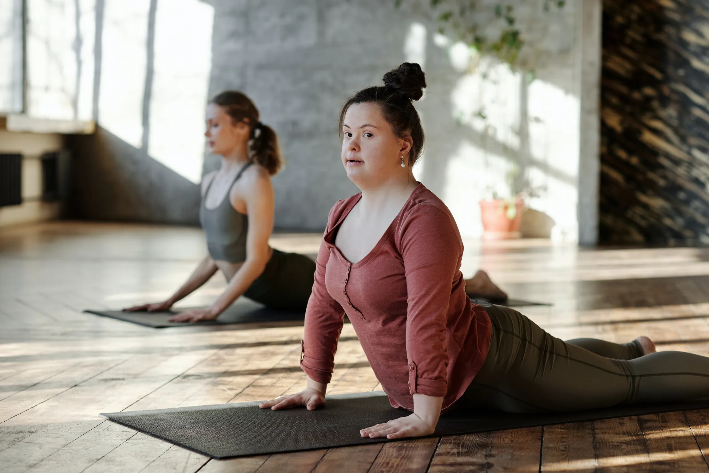 Two women doing yoga in a well-lit room