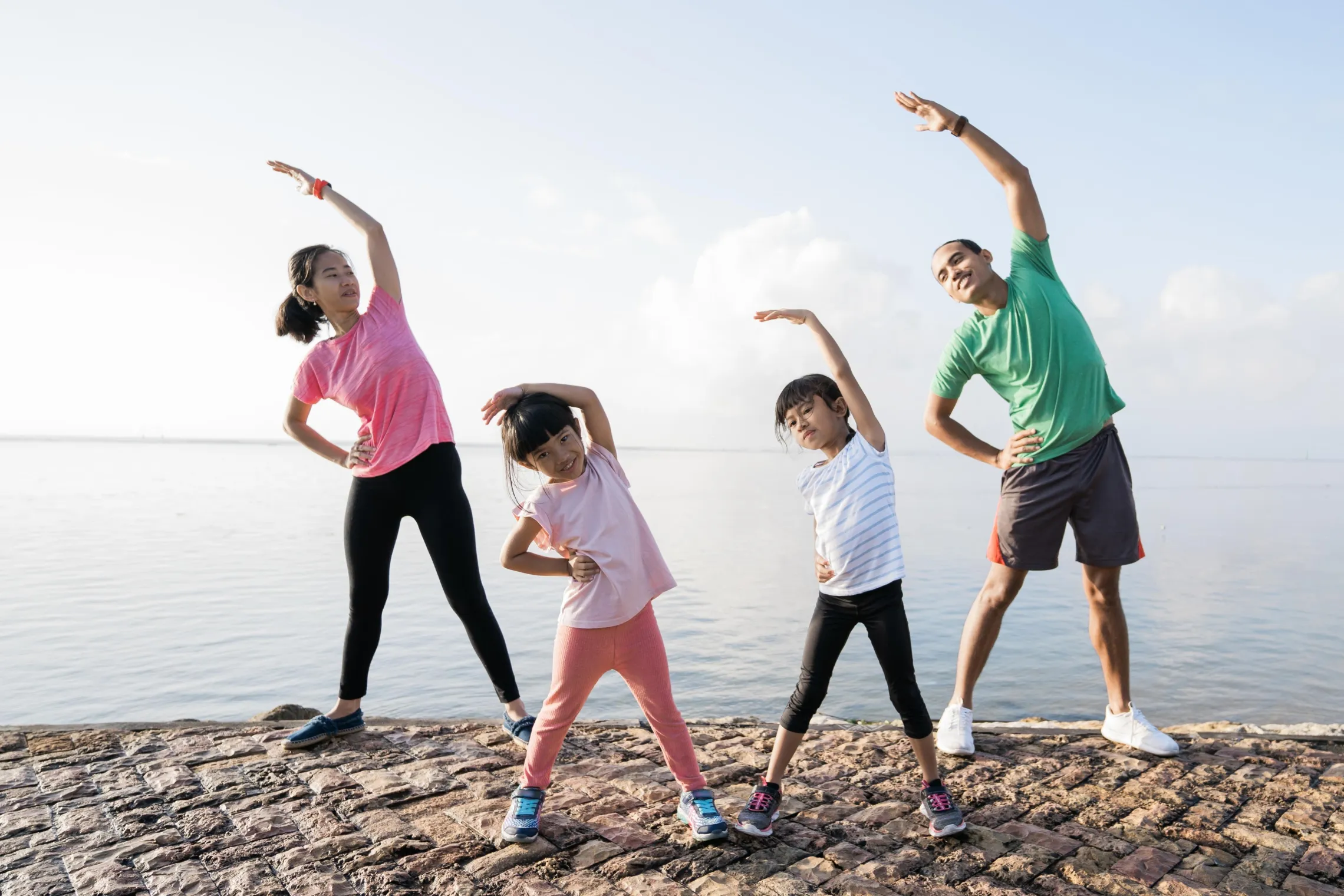 A happy family doing some exercises on a beach by the lake