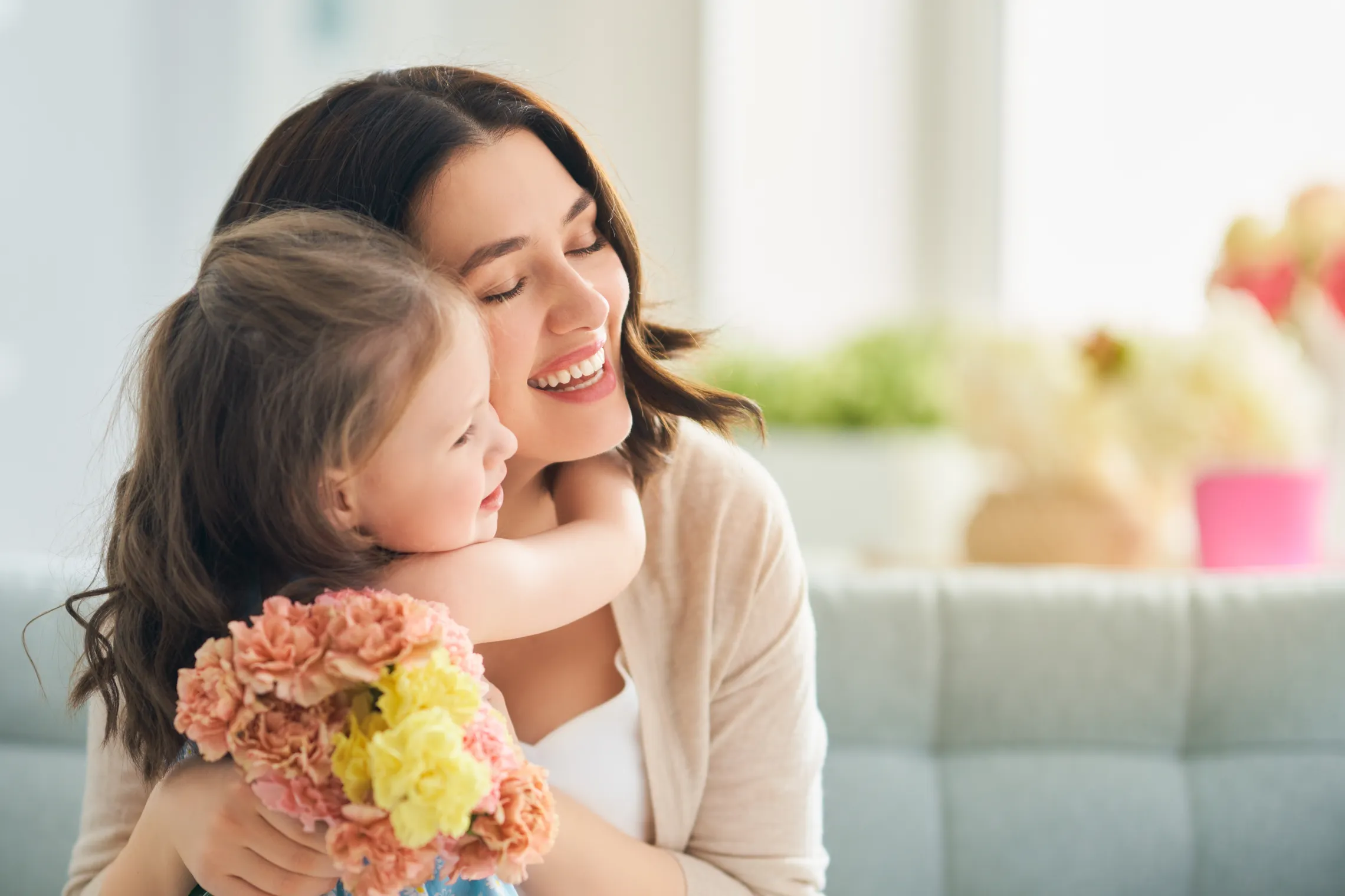 Mom and her daughter hugging while holding flowers