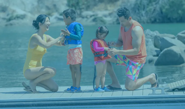 Photo shows family putting on life jackets near water.