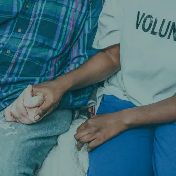 Photo shows two people holding hands.